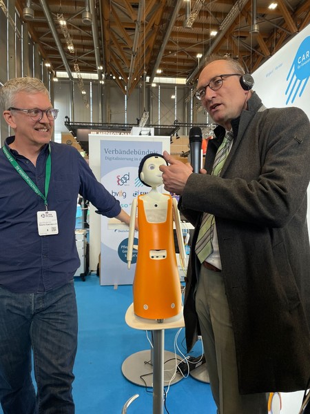Berhard Seidenath macht Bekanntschaft mit  Navel - dem KI-gesteuerten Empathie-Roboter in der Pflege. (Foto: N&uuml;rnbergMesse Frank Boxler)
